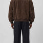 A model shown from the back wearing a jackero brown suede jacket and black wide-leg trousers against a light gray studio background.