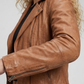 Macro detailed focus capture showing the authentic honey tan full-grain texture paired with high-shine metallic zippers on the biker jacket.