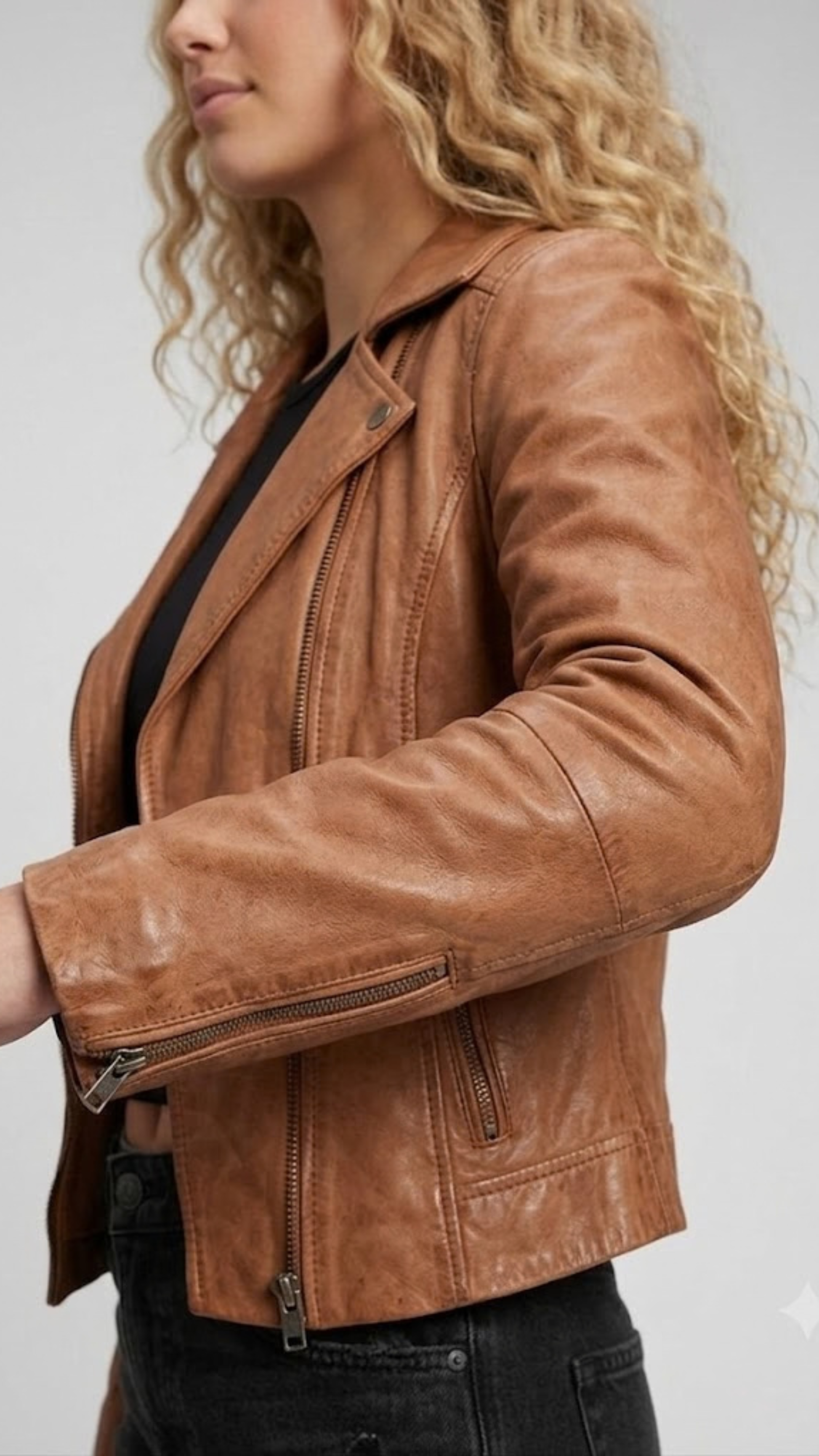 Macro detailed focus capture showing the authentic honey tan full-grain texture paired with high-shine metallic zippers on the biker jacket.