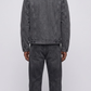 A model shown from the back wearing a washed charcoal denim jacket with white shearling and against a neutral gray background.