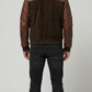 Straight-on back view of a structured brown quilted suede jacket highlighting its tailored fit and clean panel lines on a grey backdrop.