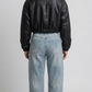 back-angle profile view of a regular fit cropped black leather outerwear showing clean back construction and a sharp, elevated silhouette.
