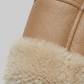 Close-up of a light beige leather jacket with soft cream fur lining on a light gray background