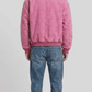 Elegant rose pink soft suede bomber jacket layered over a neutral tee, perfect for an effortlessly clean smart-casual outfit.