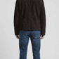 Regular fit dark brown suede shearling jacket layered over a casual knitted sweater for a modern urban aesthetic.