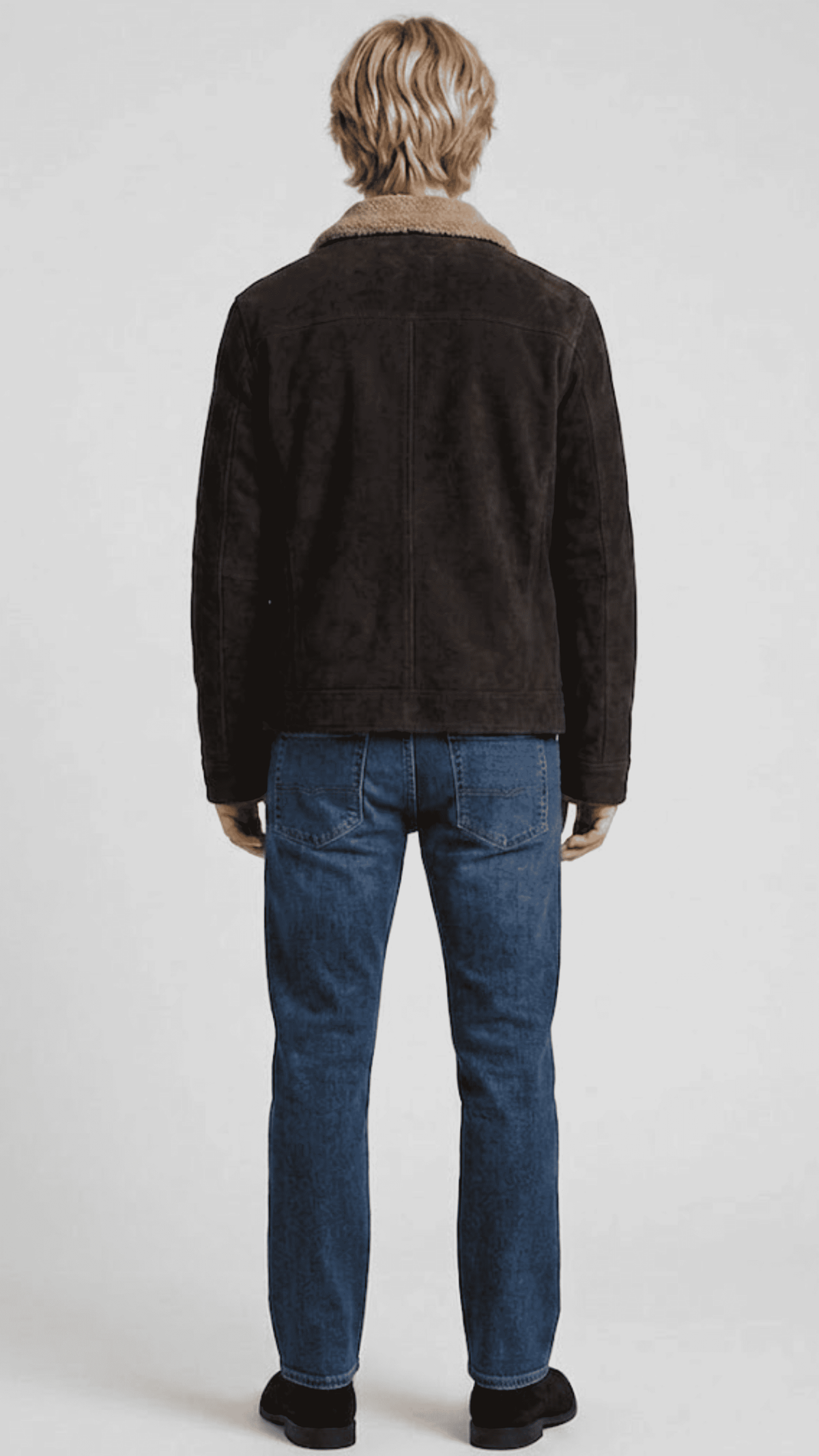 Regular fit dark brown suede shearling jacket layered over a casual knitted sweater for a modern urban aesthetic.
