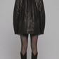 A model shown from the back wearing a black leather jacket, sheer black tights, and black knee-high boots against a neutral gray studio background.