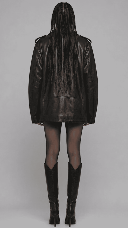 A model shown from the back wearing a black leather jacket, sheer black tights, and black knee-high boots against a neutral gray studio background.
