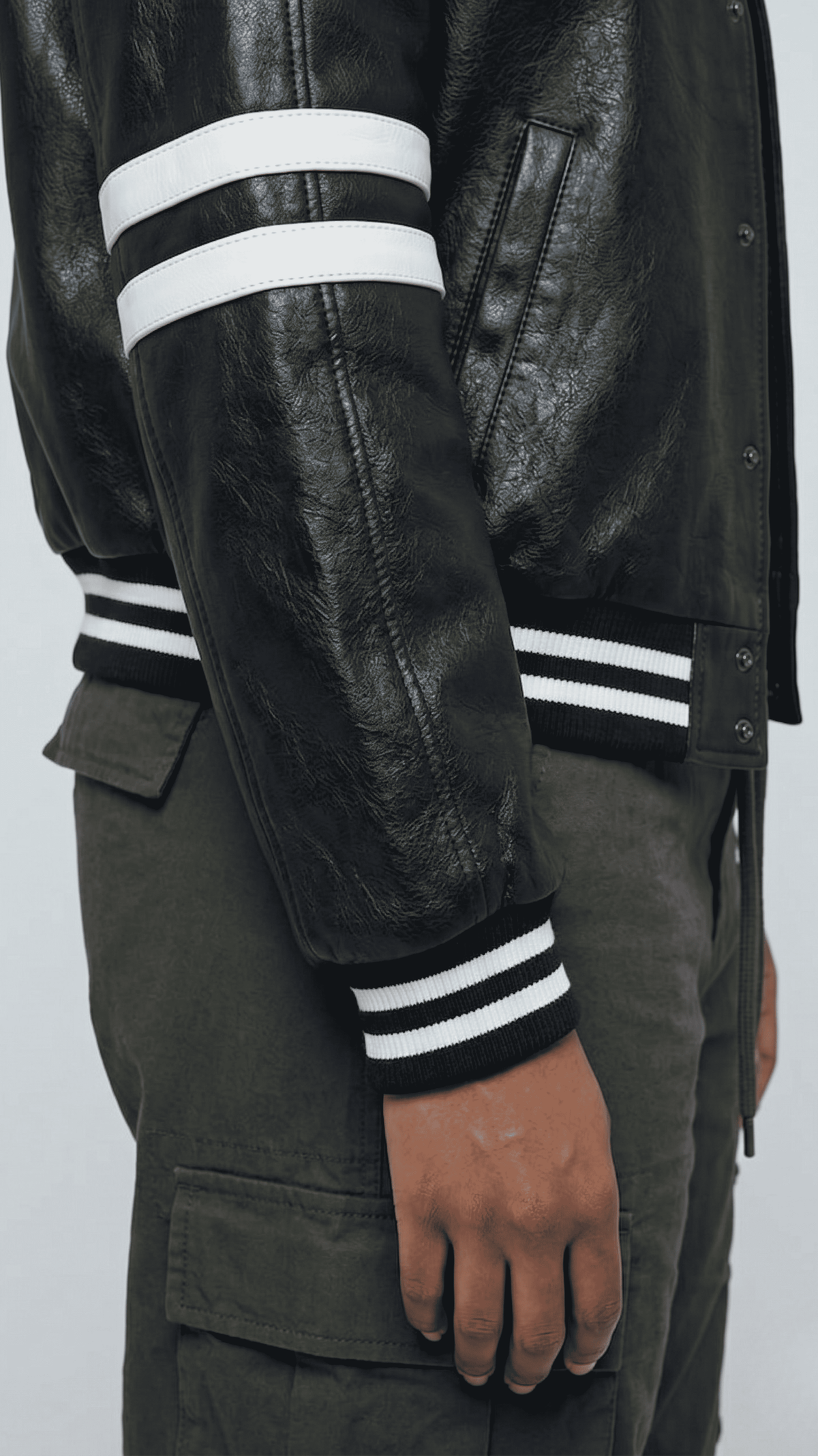 Close-up detail of the high-quality genuine black leather texture and stitching on a premium bomber racer jacket.