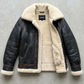 the heavy-duty metal zipper integrated seamlessly with the premium black leather and cream fur inner lapel.