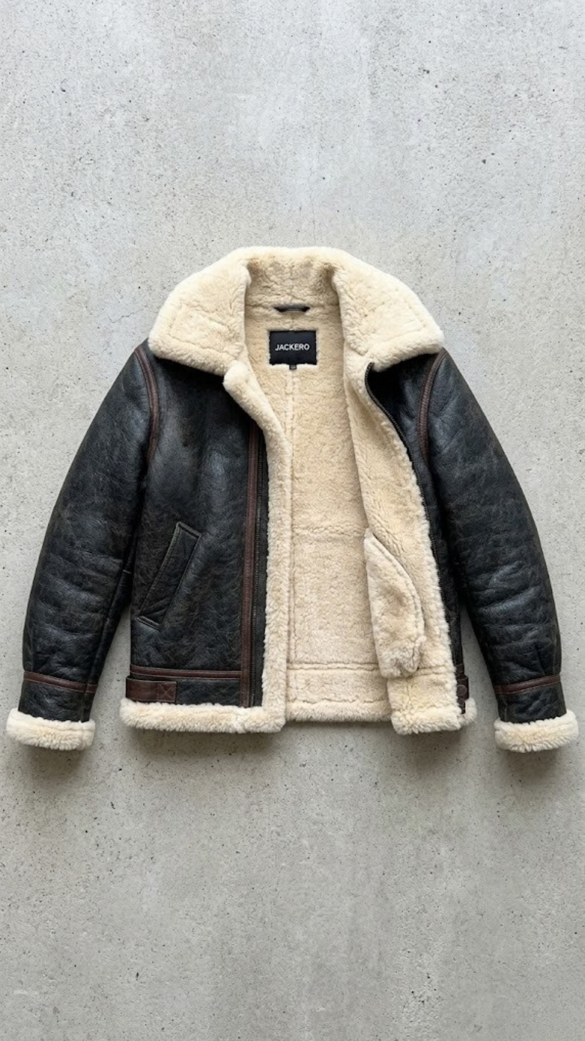 the heavy-duty metal zipper integrated seamlessly with the premium black leather and cream fur inner lapel.