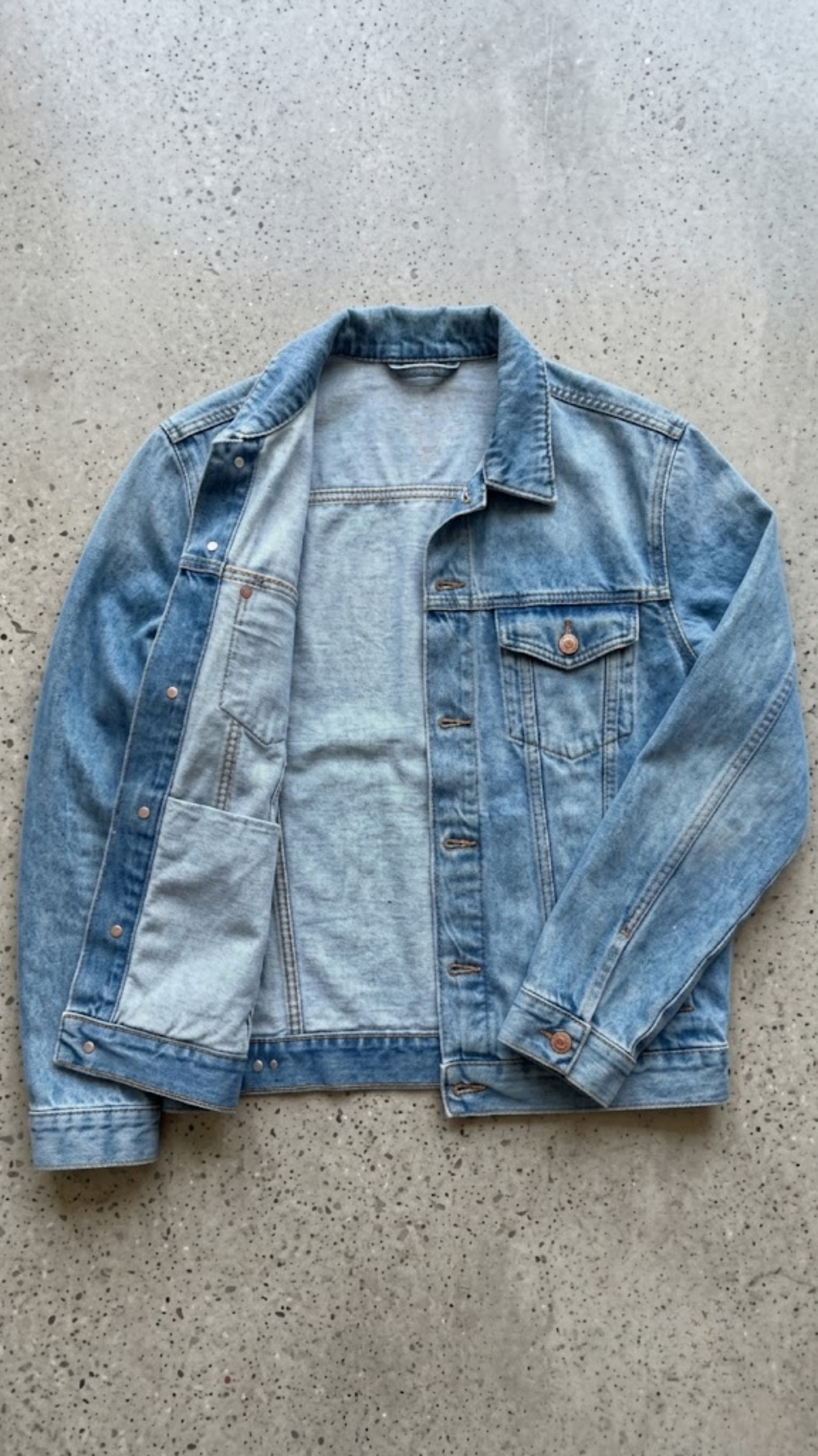 A burgundy leather moto jacket with a black interior lining, laid flat on a textured gray concrete surface. The brand name 'JACKERO' is visible on the inner neck label.