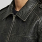 Close-up detail focusing on the subtle faded highlights of the vintage-wash black leather material and heavy-duty zipper hardware.