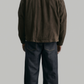 Straight-on silhouette of a structured dark brown cotton utility jacket displaying symmetrical pockets and a clean waistline fit.