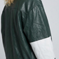 Close-up micro detail focusing on the premium dark green leather texture contrasted with the stitched white stripe accents and hardware.