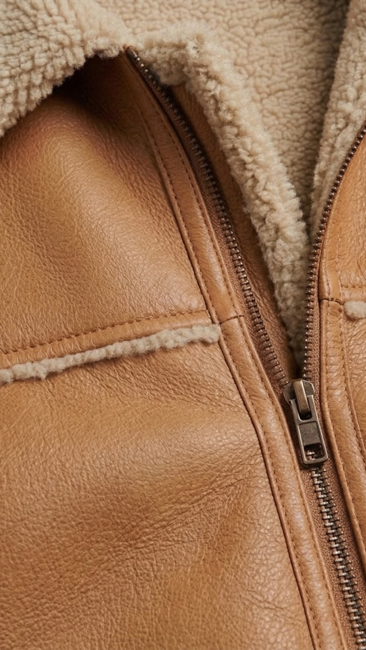 Close-up of a brown leather jacket with a zipper