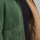 Green jacket with brown sherpa lining worn by a person on a neutral background