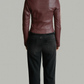 Person wearing a dark burgundy leather jacket and black pants on a plain background