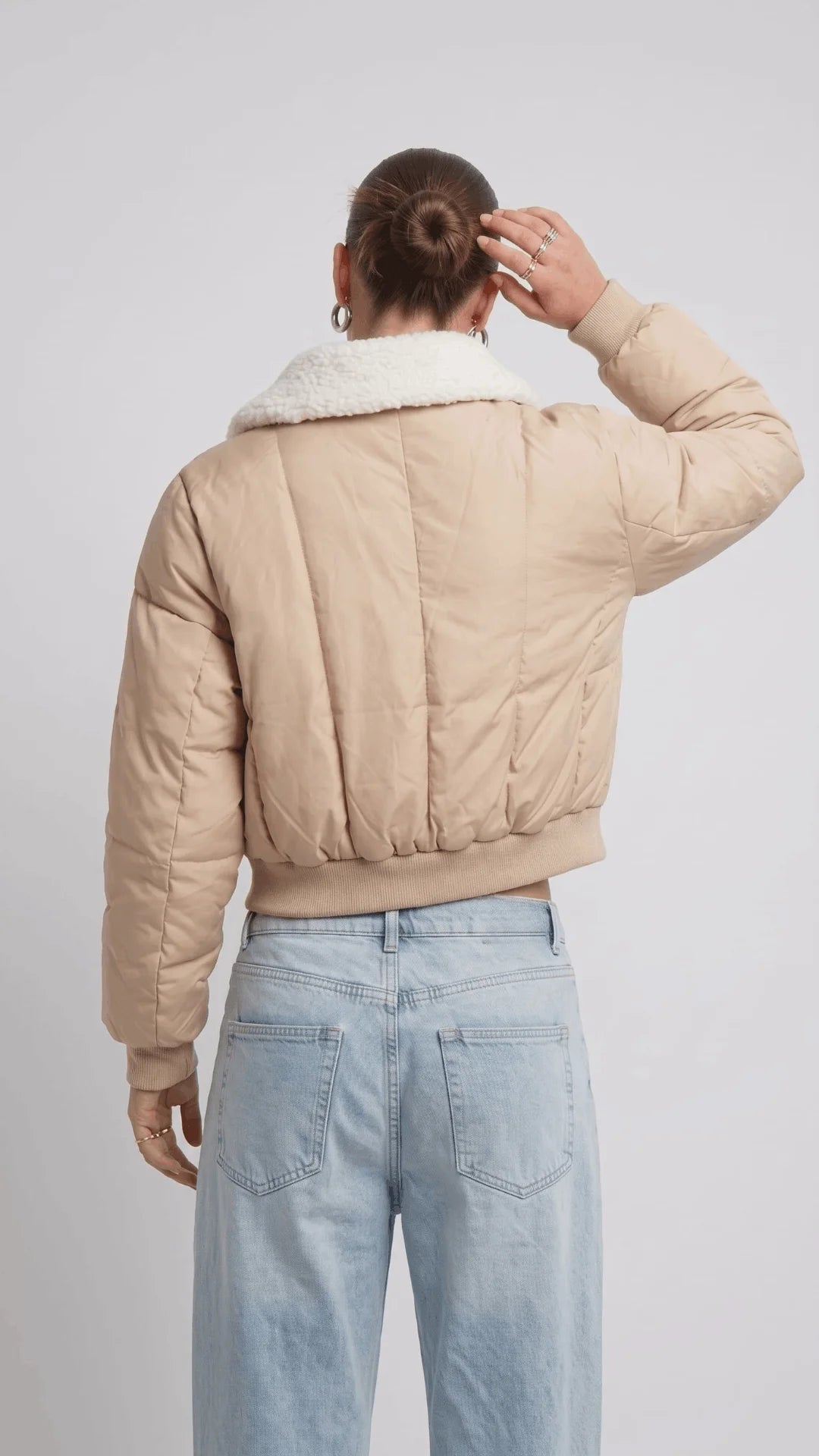 Detailed view of the structured neat collar stitching and precise finished hemline on a premium light beige cropped fashion jacket.