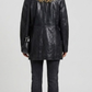 back-angle profile view of a regular fit black leather trench coat displaying smooth drape, neat hemline, and comfortable tailoring alignment.