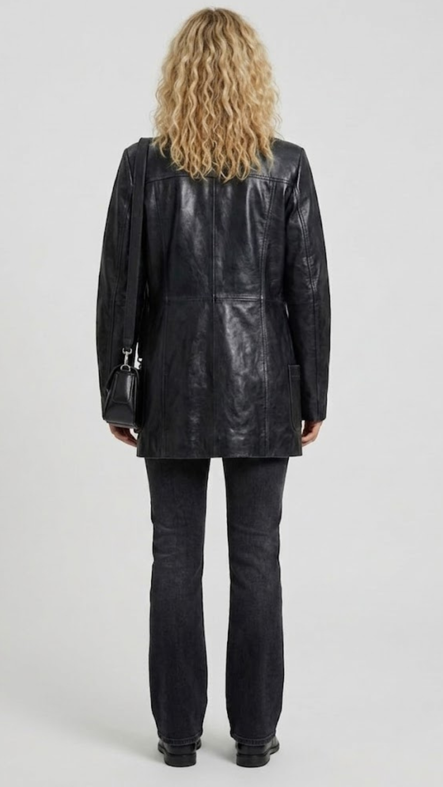 back-angle profile view of a regular fit black leather trench coat displaying smooth drape, neat hemline, and comfortable tailoring alignment.