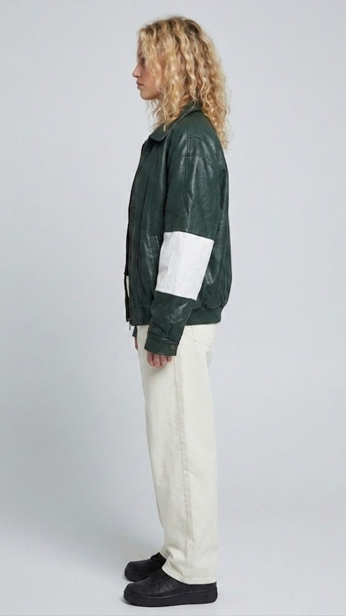 the minimalist collar construction and sporty shoulder paneling of a dark green striped leather jacket.