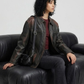 Detailed studio shot showcasing the premium buttons, chest pockets, and washed finish of a black leather trucker coat.