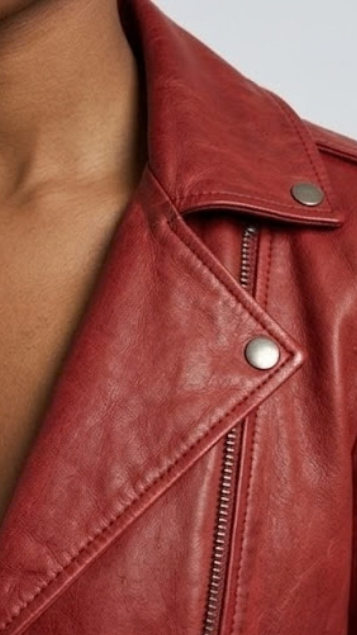 Close-up micro detail focusing on the premium texture of red genuine leather contrasted with heavy-duty silver metallic zippers.