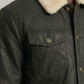 Close-up shot of the premium cream shearling collar on a sleek black leather trucker coat.