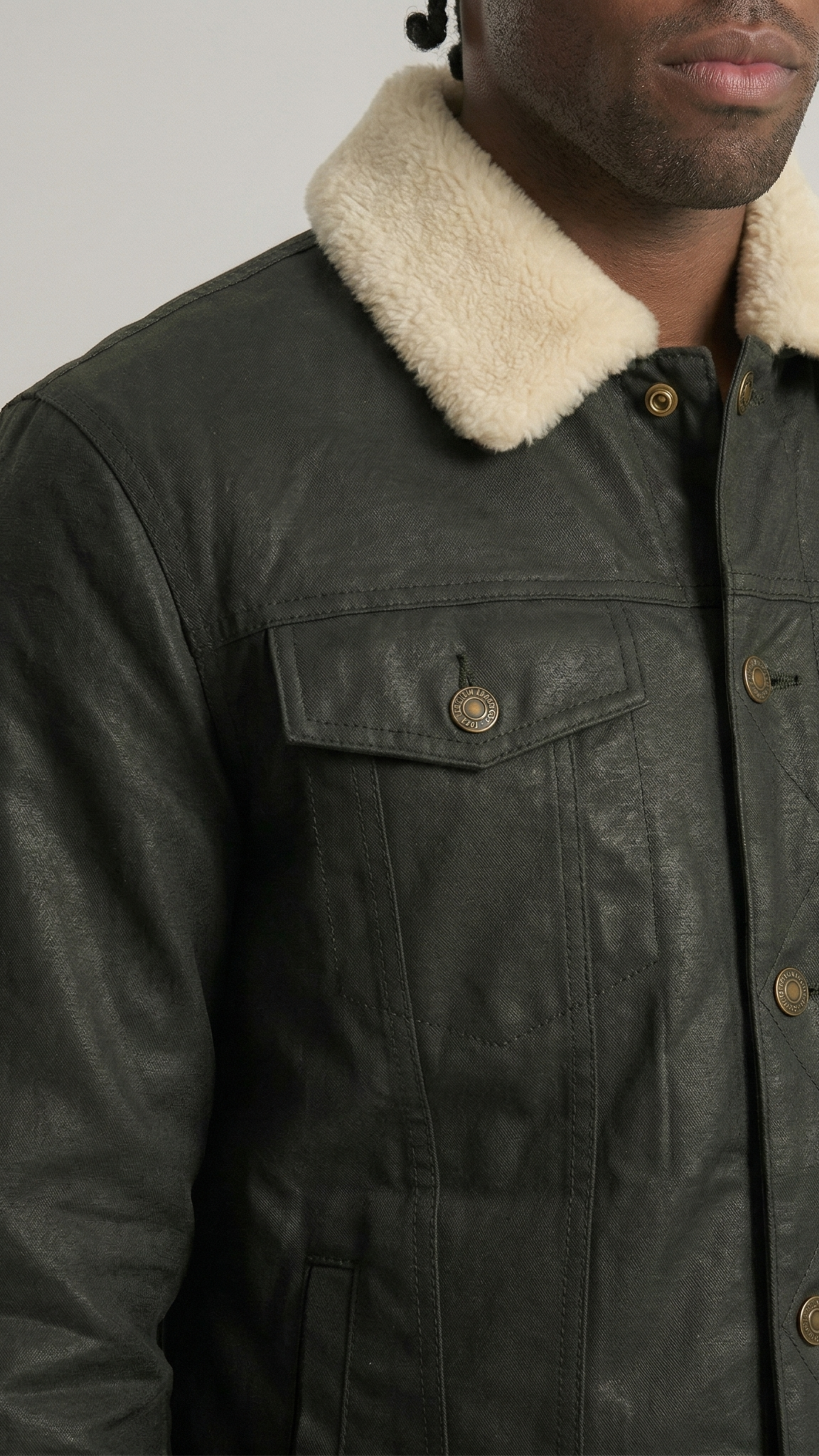 Close-up shot of the premium cream shearling collar on a sleek black leather trucker coat.