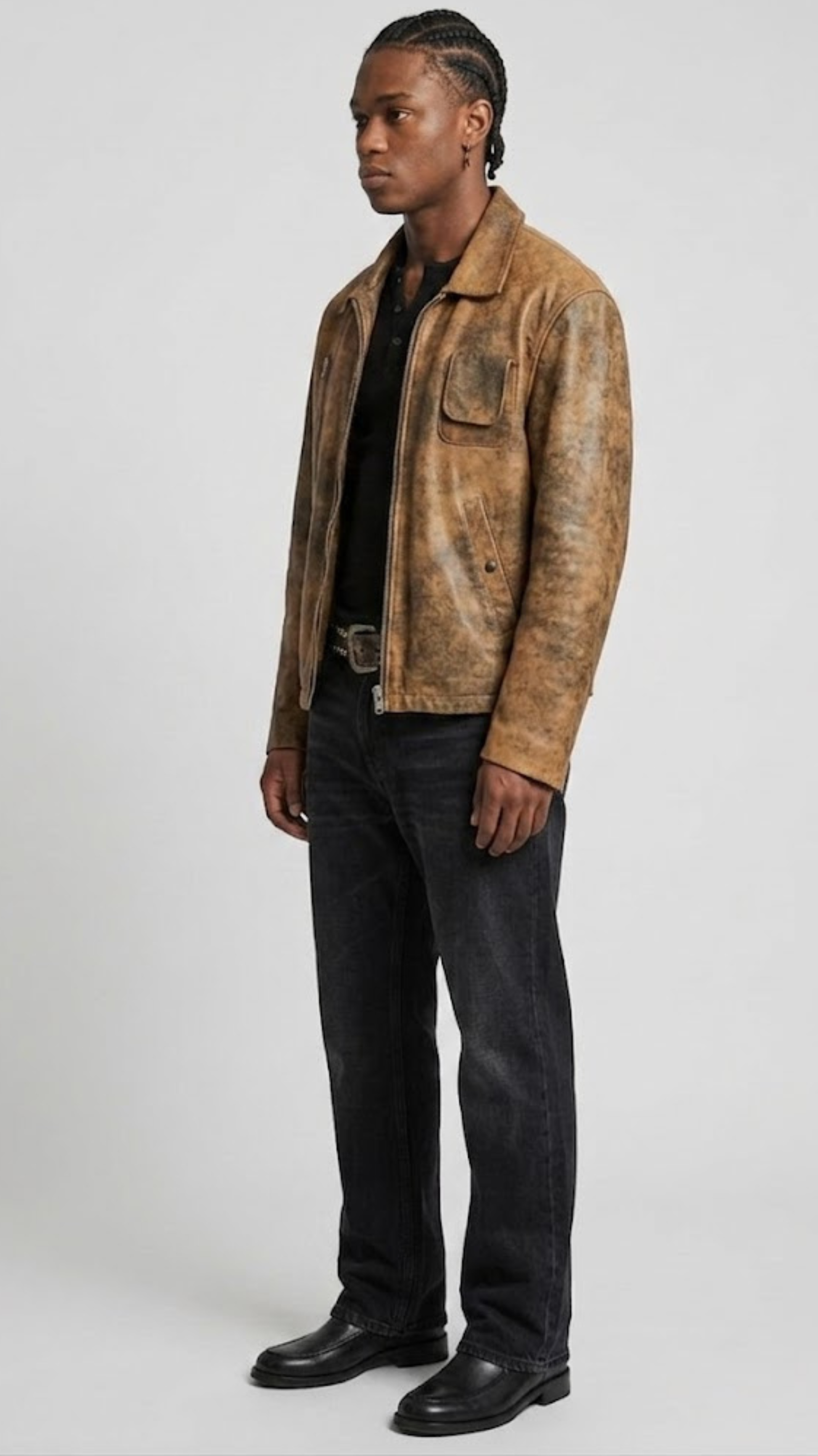 A man modeling a distressed brown leather jacket with a tan and black mottled pattern, worn over a black shirt and dark jeans, against a light gray studio background.