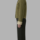 Person wearing a green jacket with a white collar on a gray background