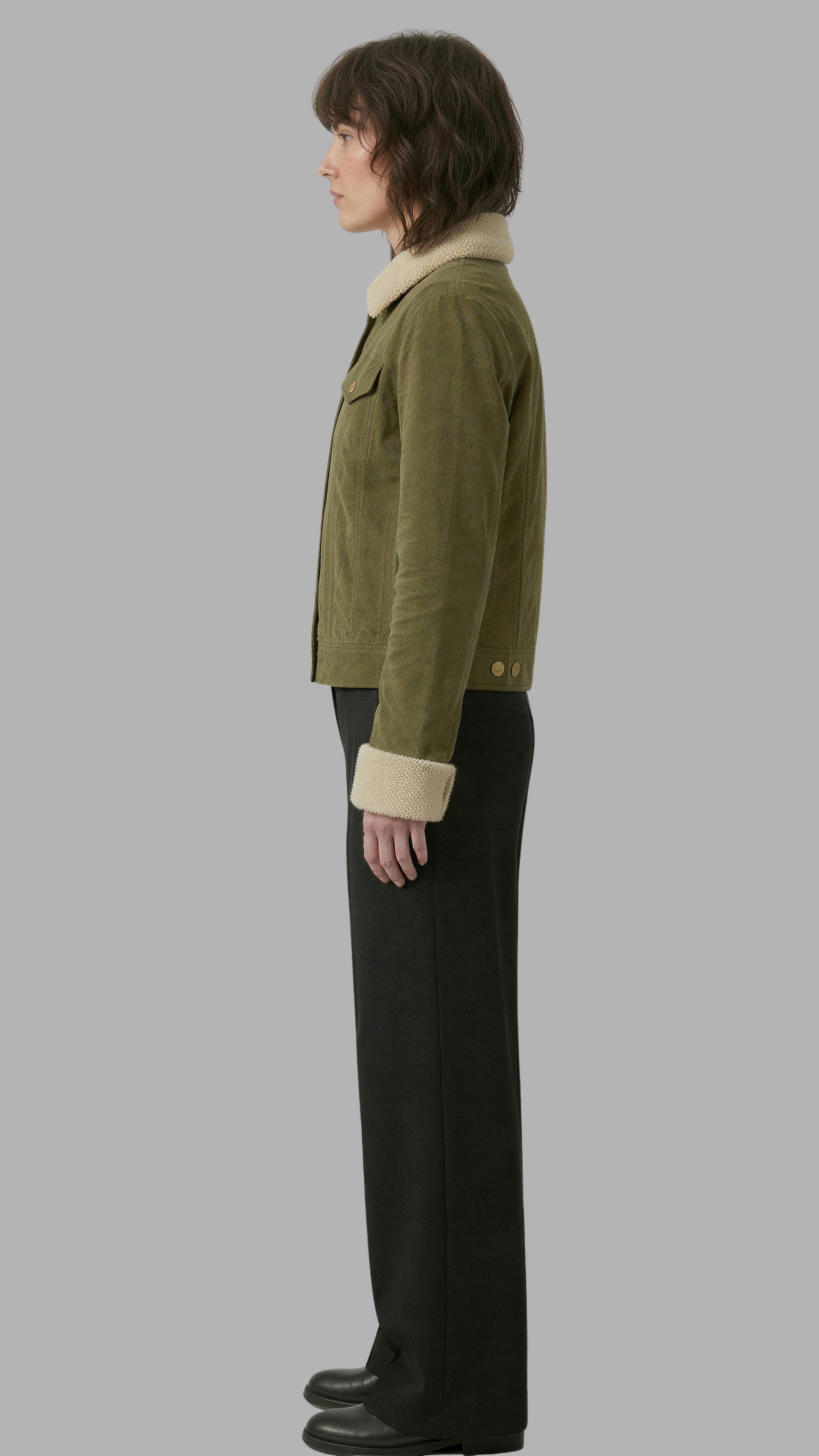 Person wearing a green jacket with a white collar on a gray background