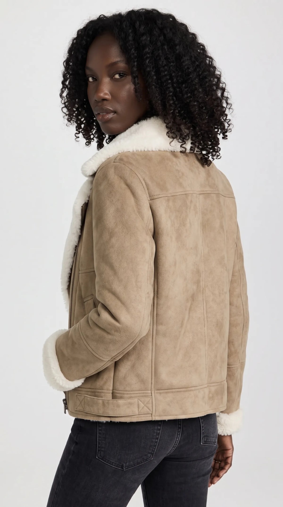 The sand-beige suede aviator jacket features clean back-panel stitching, a structured waist-length cut and contrasting ivory shearling around the collar, cuffs and lower edge. Its muted neutral color and softly textured finish make it an appealing statement layer for contemporary winter wardrobes and understated luxury styling.