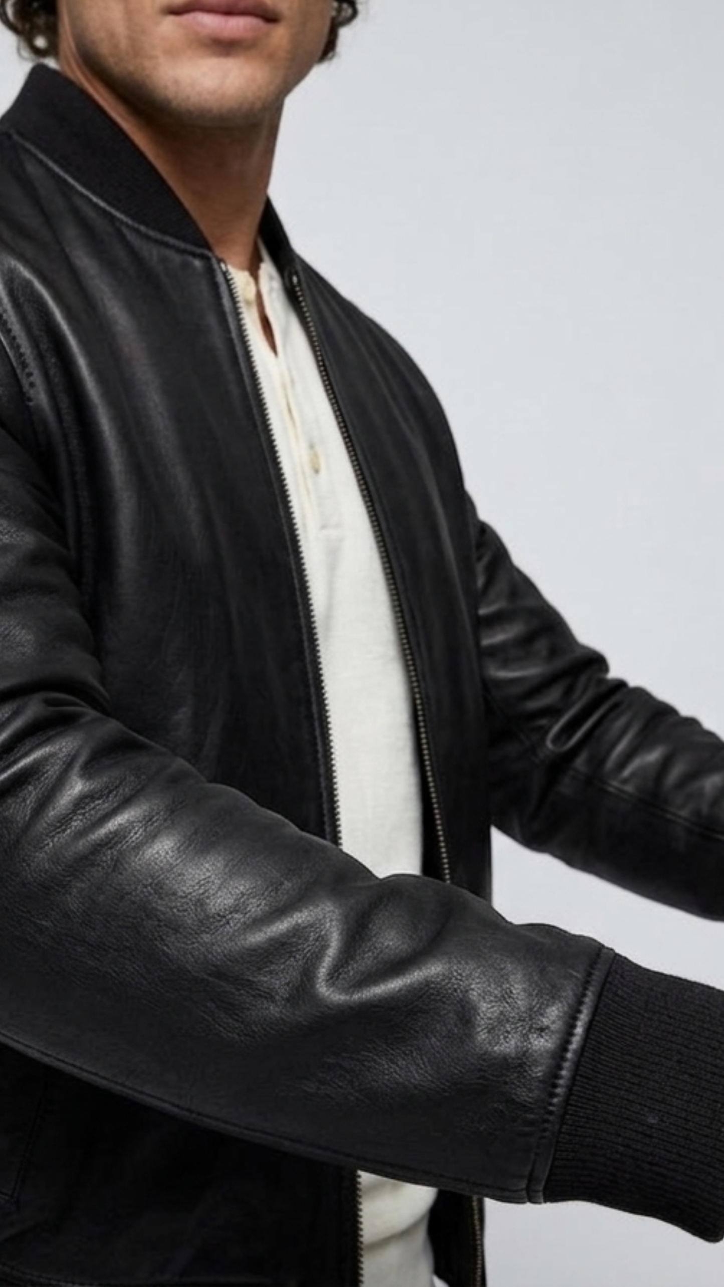 Macro detailed focus capture capturing the luxurious fine-grain texture and rich subtle sheen of the authentic black leather bomber fabric.