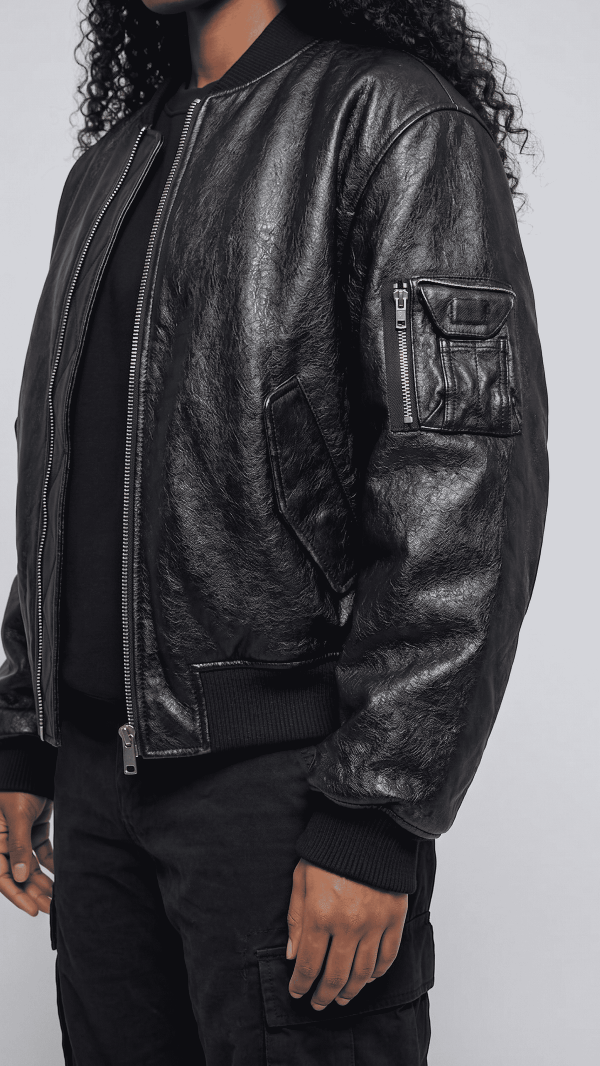 Detailed macro view of the high-quality elastic rib-knit cuff and premium genuine leather texture on a sleek bomber jacket sleeve.