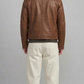 Symmetrical back view of a structured brown leather coat, highlighting the clean shoulder yoke and minimalist, tailored fit alignment.