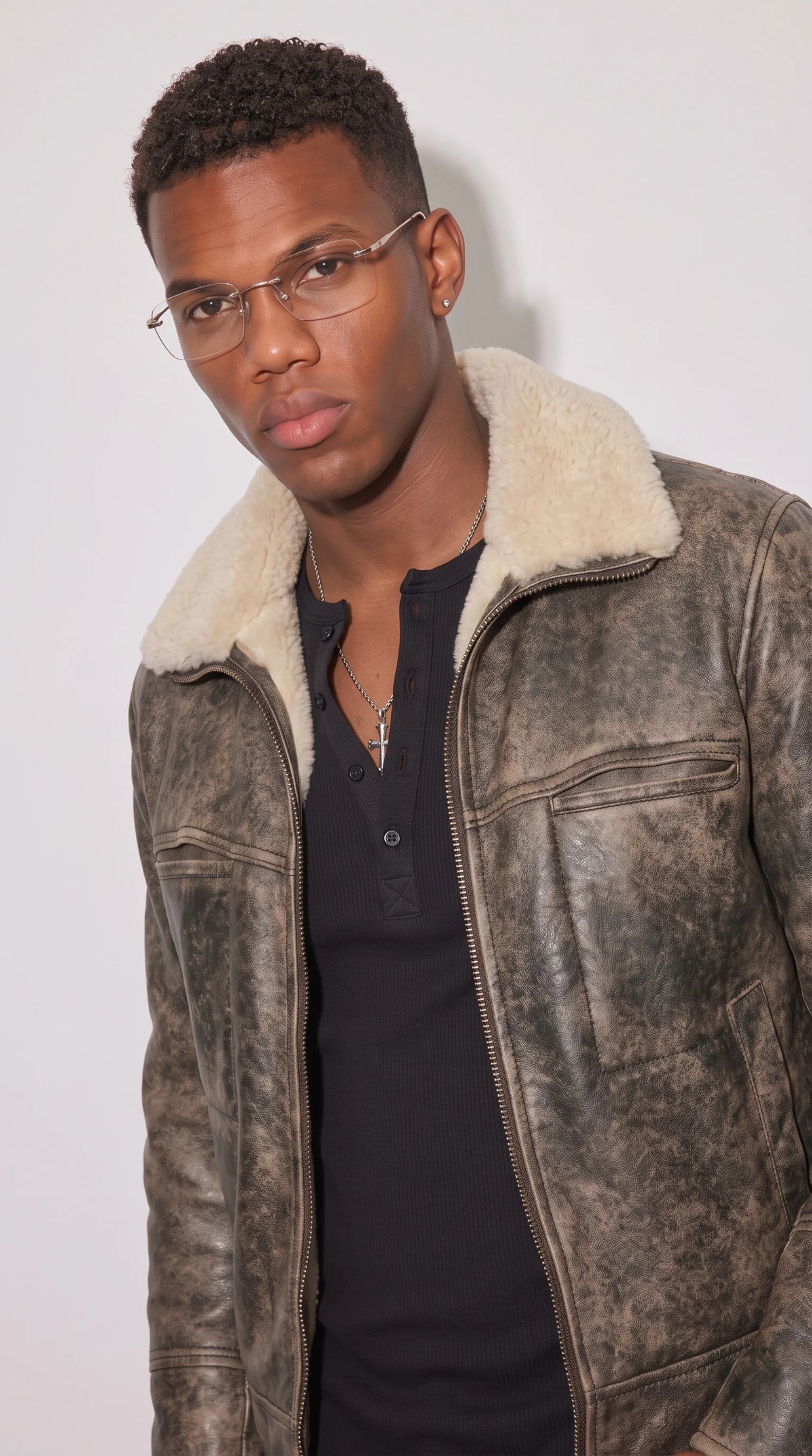 Close-up of a smoky-grey distressed genuine leather flight jacket featuring a thick ivory faux-shearling collar, two horizontal zipped chest pockets, dark tonal seam stitching and a sturdy industrial front zipper, creating a distinctive vintage aviator design with contrasting textures.