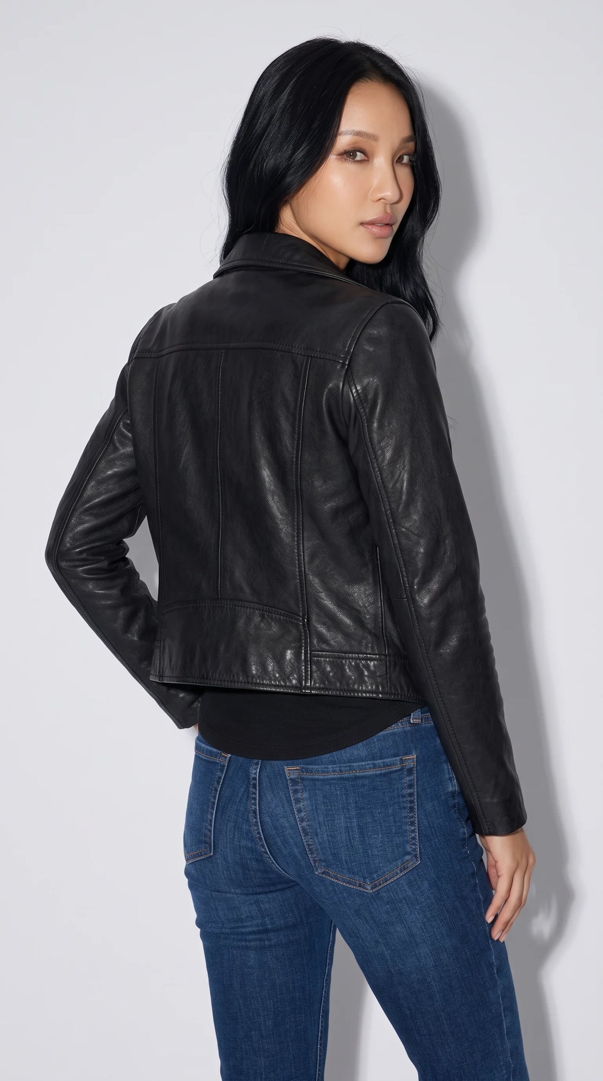 Smooth black genuine leather jacket featuring a defined shoulder yoke, neat vertical back-panel seams, shaped sleeves and a cropped waist-length silhouette, creating a streamlined leatherwear look that pairs naturally with dark or indigo denim.