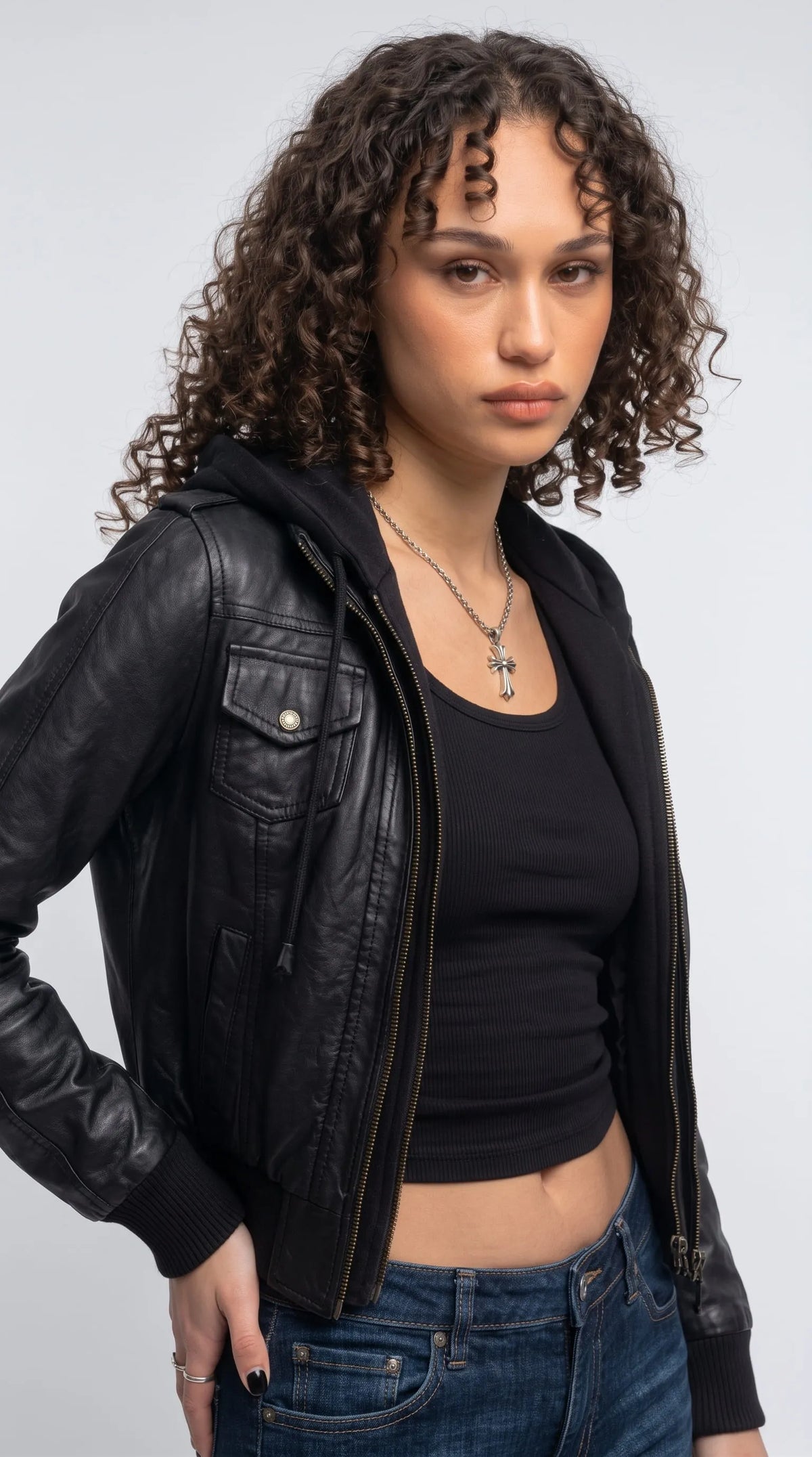 Smooth black genuine leather hooded bomber featuring a buttoned chest flap pocket, contrast metal zipper teeth, stitched leather panels and an adjustable cotton-blend hood, combining functional utility details with contemporary designer-inspired fashion.
