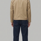 Back view of a structured beige cotton coat highlighting squared shoulders and precise central seam alignment.