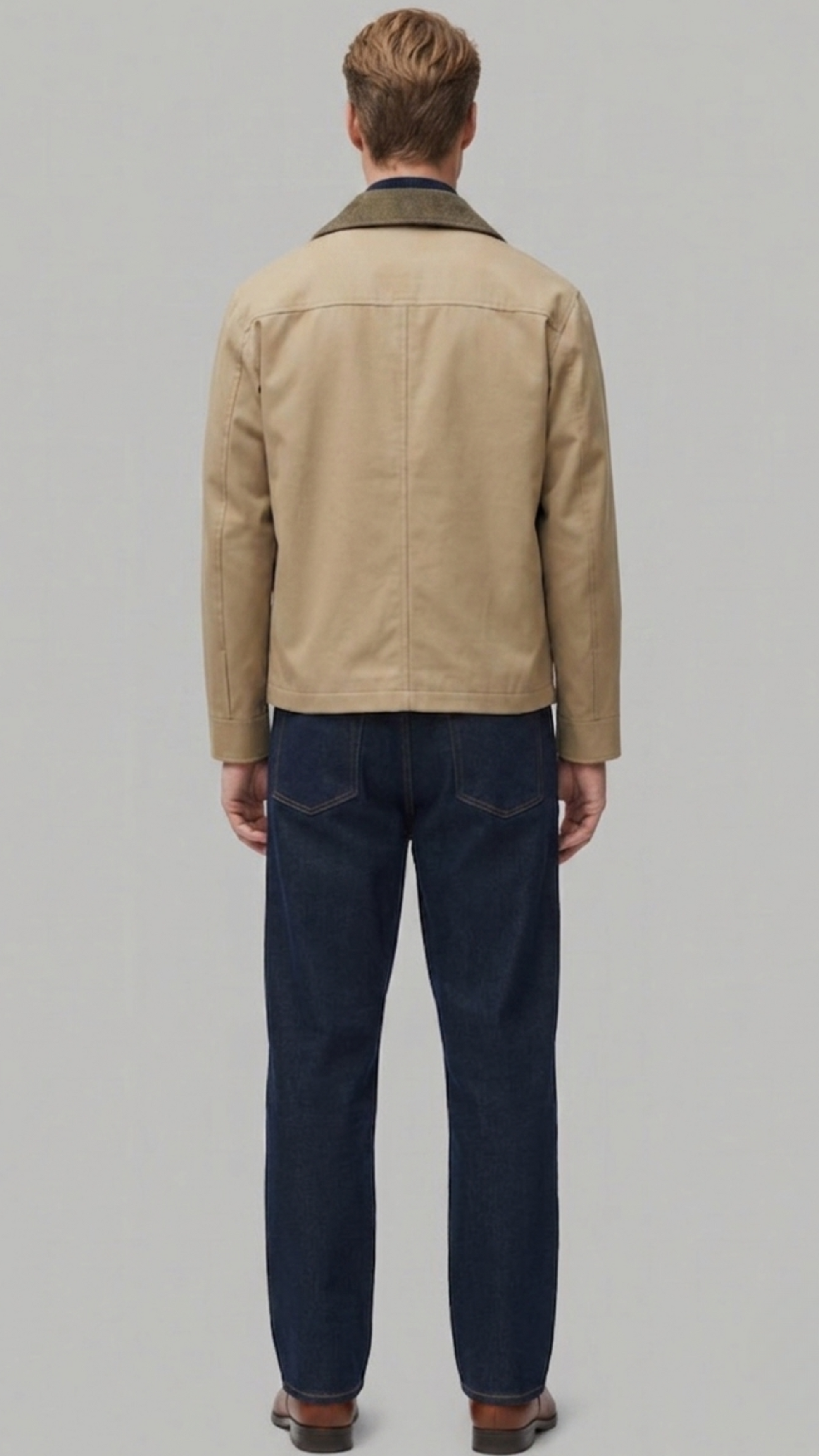 Back view of a structured beige cotton coat highlighting squared shoulders and precise central seam alignment.