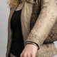 Close-up of a dark brown leather jacket with a high collar and a horizontal cream stripe detail on the chest.
