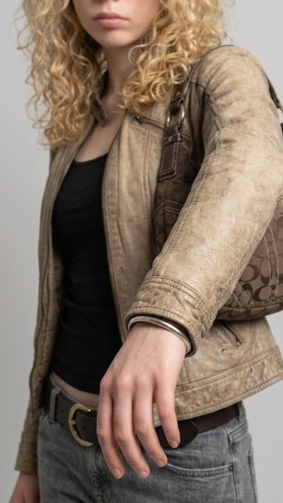 Close-up of a dark brown leather jacket with a high collar and a horizontal cream stripe detail on the chest.