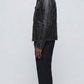 The simple band collar design, hidden zip path, and clean tailored cuffs of a premium black leather jacket.