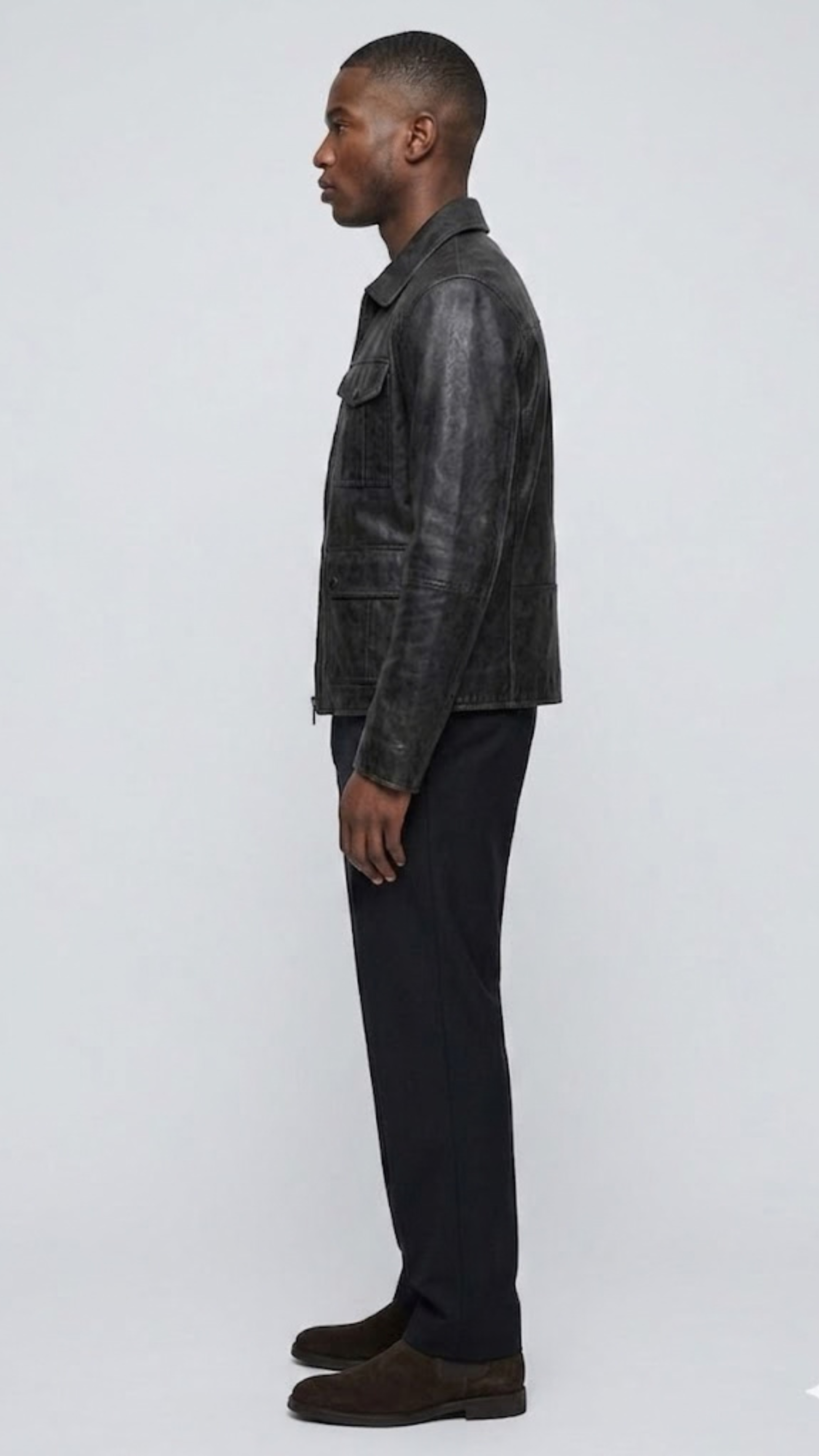 The simple band collar design, hidden zip path, and clean tailored cuffs of a premium black leather jacket.