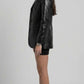Side angle of model wearing black croc print blazer displaying sleeve button cuffs and structured shoulders