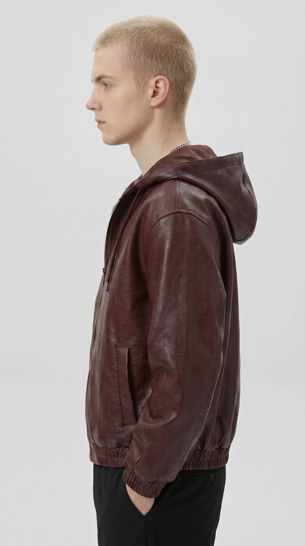 Unisex streetwear burgundy PU leather hooded jacket with ribbed cuffs, paired with black trousers and white film strip tee
