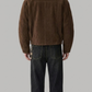 Rear view of a men's classic dark brown leather jacket with shearling lining, highlighting clean panel seams and a structured waistband.