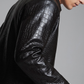 Close-up shot of premium embossed crocodile skin pattern on a black leather jacket.
